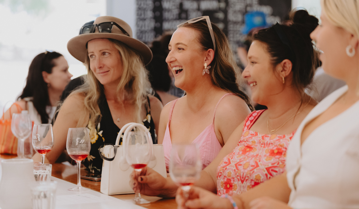 Group of people smiling and drinking wine 